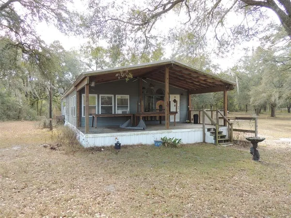 a view of a house with backyard and chairs