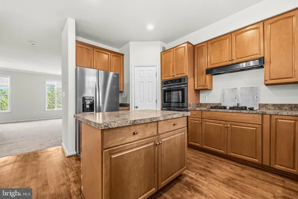 a kitchen with stainless steel appliances granite countertop a refrigerator a stove and a sink with wooden cabinets