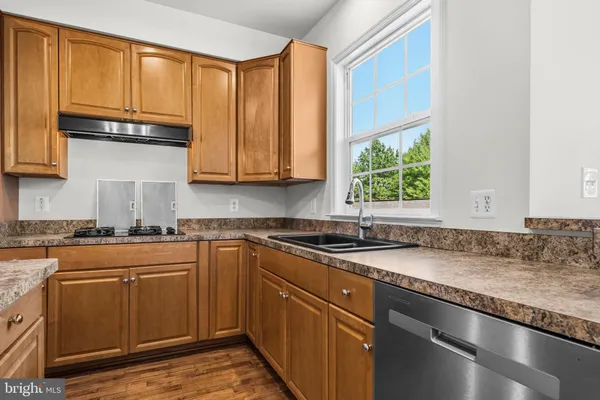 a kitchen with granite countertop stainless steel appliances a sink window and cabinets