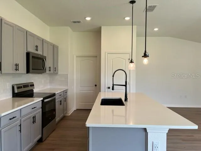 a kitchen with stainless steel appliances kitchen island a white counter top space cabinets and a wooden floor