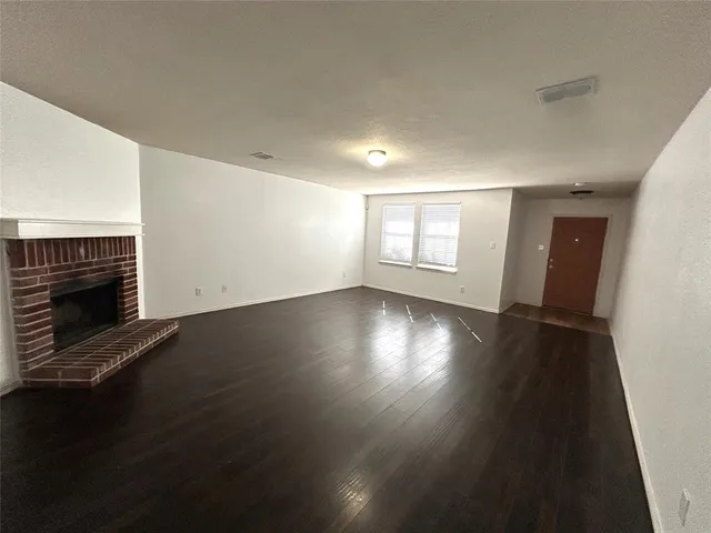 an empty room with wooden floor and fireplace