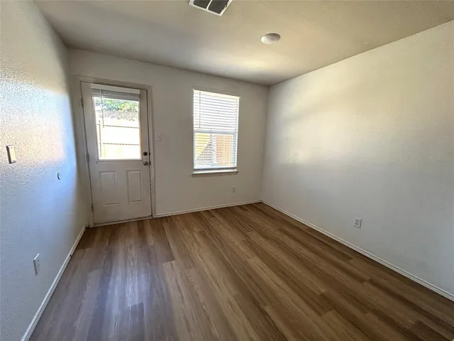 an empty room with wooden floor and windows