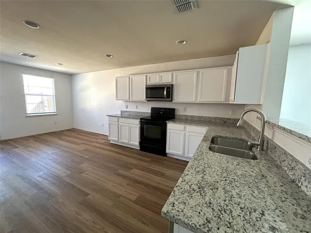 a kitchen with granite countertop a stove a sink and a refrigerator