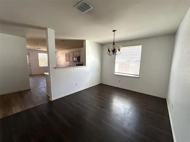 an empty room with wooden floor cabinet and windows