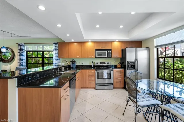 a kitchen with stainless steel appliances kitchen island granite countertop a refrigerator a stove top oven a sink dishwasher and couches with wooden floor