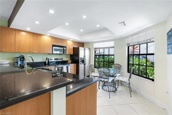 a kitchen with stainless steel appliances granite countertop a sink counter space cabinets a stove and a window