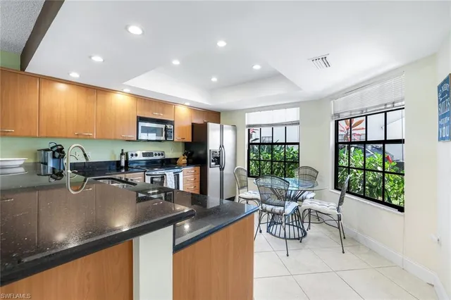 a kitchen with stainless steel appliances granite countertop a sink counter space cabinets a stove and a window