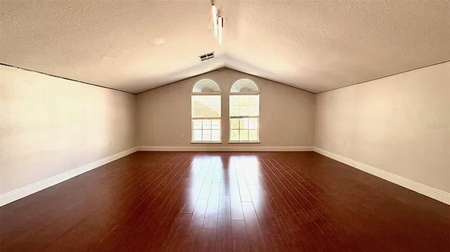 an empty room with wooden floor and window