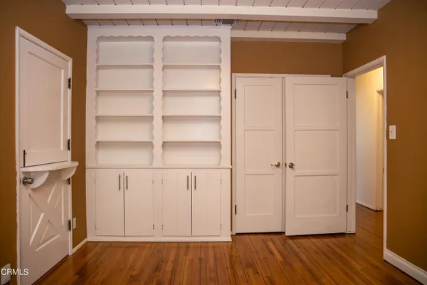 a view of an empty room with wooden floor and closet