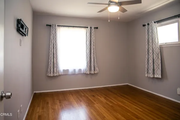 an empty room with wooden floor and windows