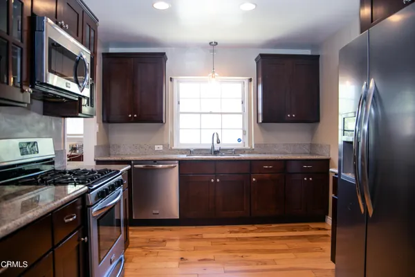 a kitchen with stainless steel appliances granite countertop a stove a sink and a microwave