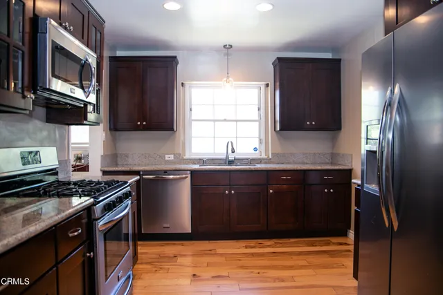 a kitchen with stainless steel appliances granite countertop a stove a sink and a microwave