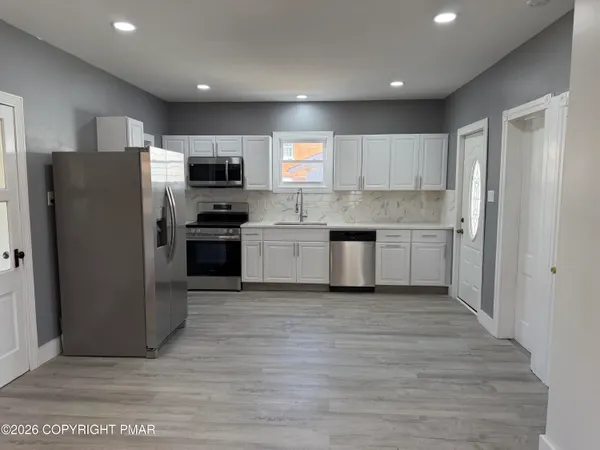 a kitchen with stainless steel appliances granite countertop a refrigerator and a stove top oven