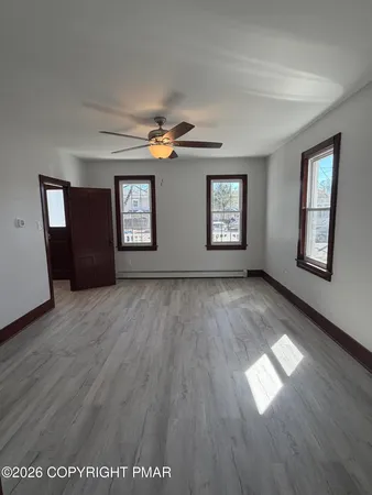 a view of empty room with wooden floor and fan