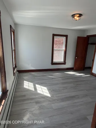 a view of an empty room with wooden floor and a window