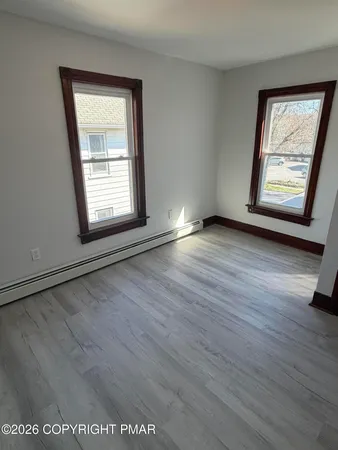 an empty room with wooden floor and windows