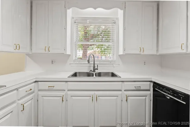 a kitchen with white cabinets and a window
