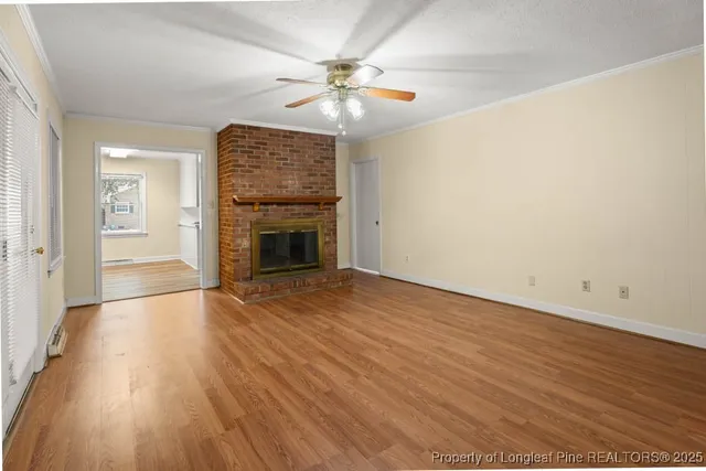 a view of an empty room with wooden floor fireplace and a window