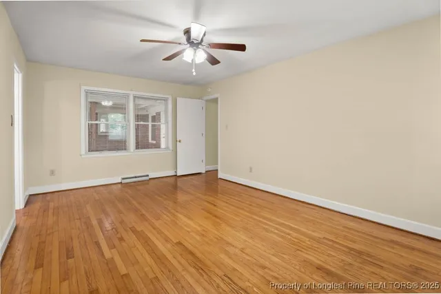 a view of an empty room with wooden floor and a window