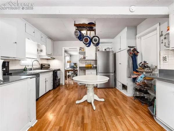 a kitchen with a sink dishwasher a dining table and chairs with wooden floor