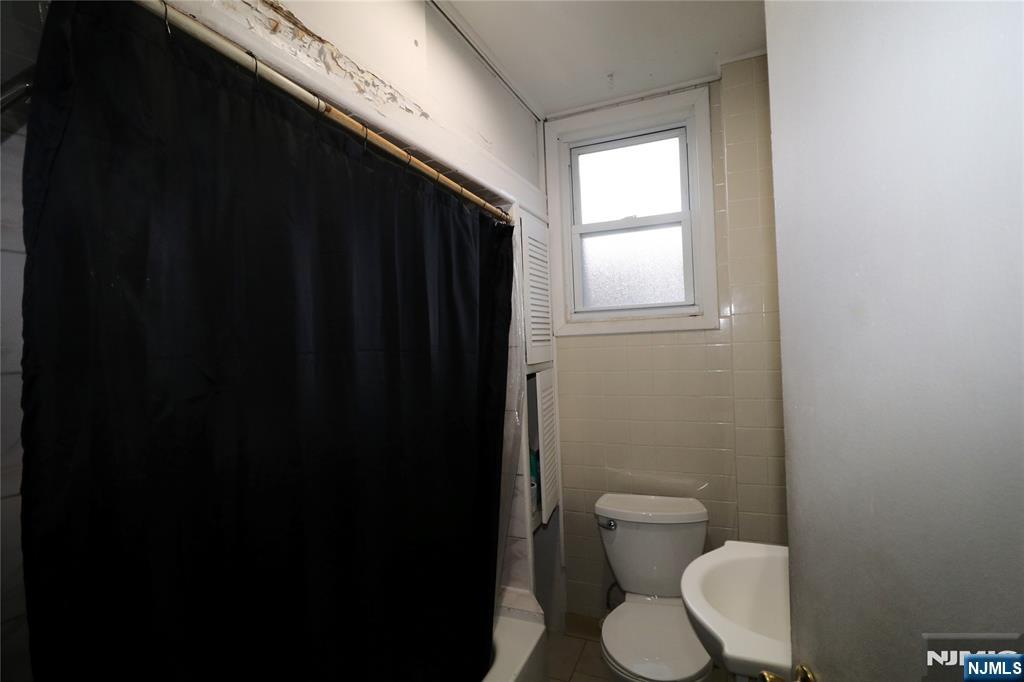 233-235 Adams Street Newark, NJ 07105 - Photo 4 of 20 a bathroom with a toilet a sink and a window