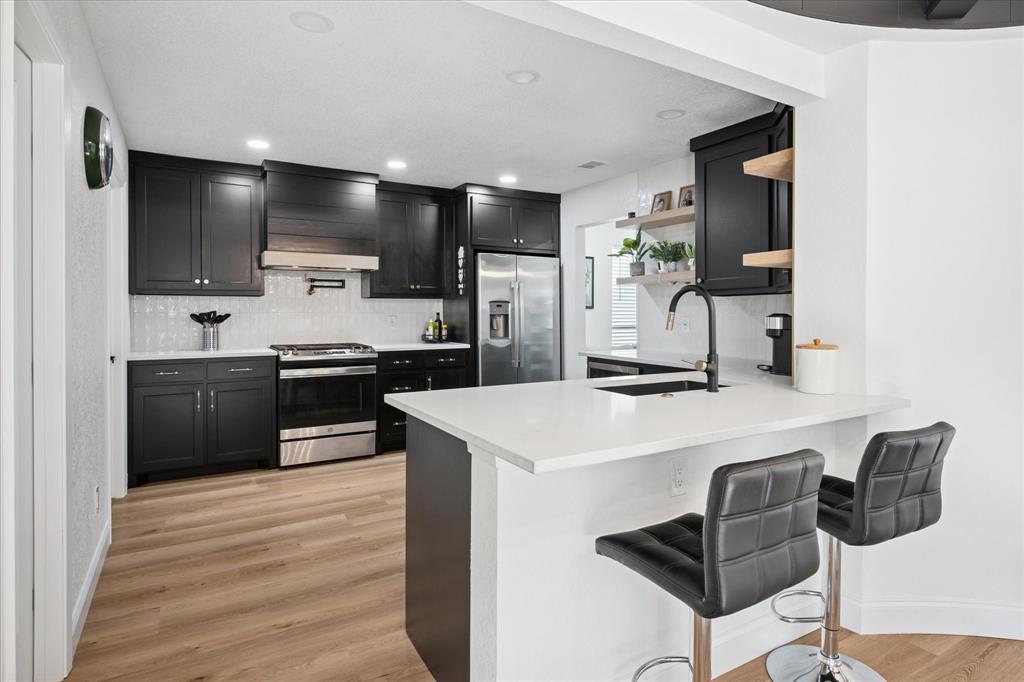 6030 Blue Mist Lane Dallas, TX 75248 - Photo 12 of 29 a kitchen with stainless steel appliances kitchen island a sink stove and refrigerator