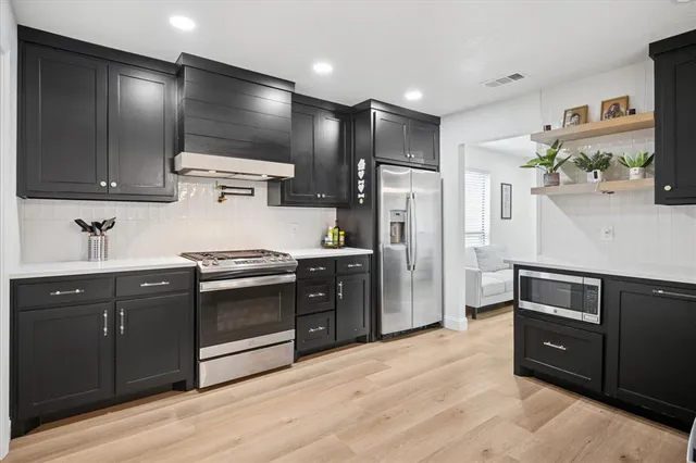 a kitchen with stainless steel appliances kitchen island granite countertop a refrigerator and a sink