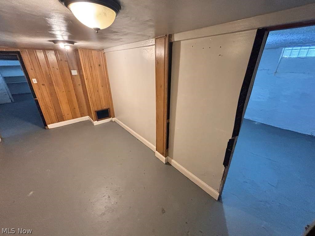 907 Rondel Road Cleveland, OH 44110 - Photo 24 of 26 Interior space featuring wood-paneled wall accents, painted concrete flooring, and flush-mount ceiling lighting