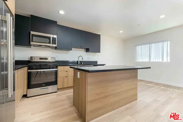 a kitchen with granite countertop a refrigerator and a stove top oven