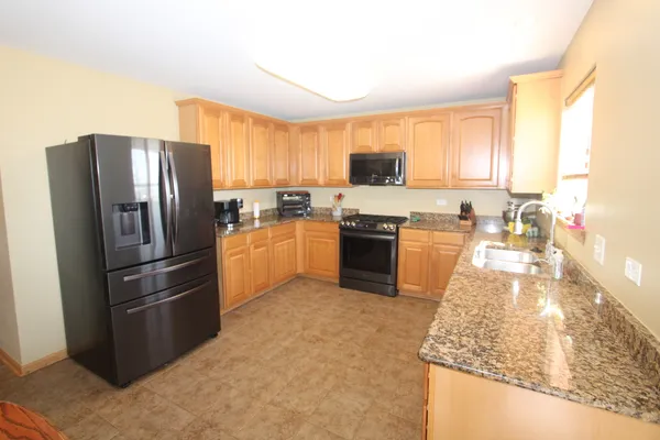 a kitchen with stainless steel appliances granite countertop a refrigerator a stove top oven a sink and dishwasher