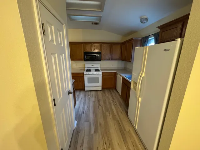 a kitchen with a refrigerator a sink and dishwasher a stove top oven with wooden floor