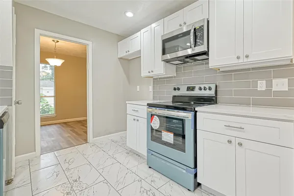 a kitchen with a stove a sink dishwasher a refrigerator and white cabinets with wooden floor