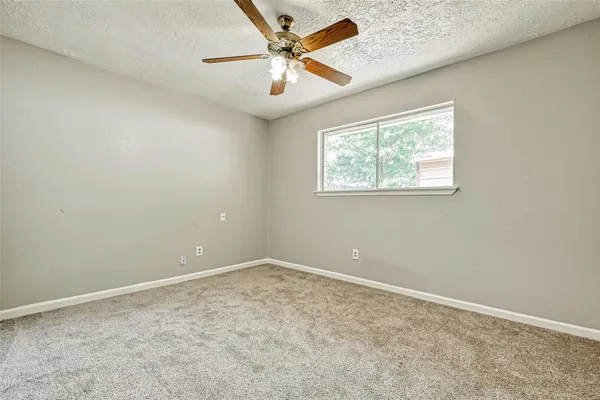 an empty room with a window and ceiling fan
