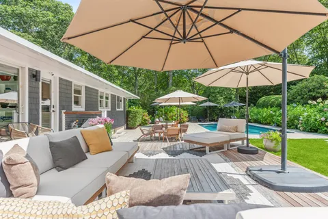 a view of a patio with couches table and chairs under an umbrella