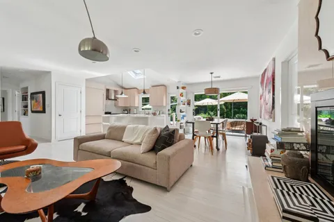 a living room with furniture kitchen view and a large window