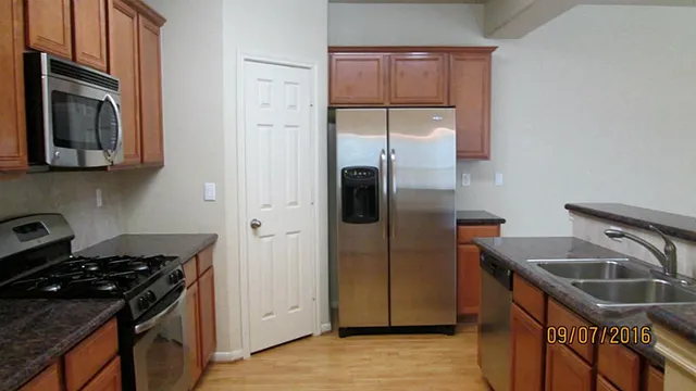 a kitchen with stainless steel appliances granite countertop a refrigerator a sink and a stove