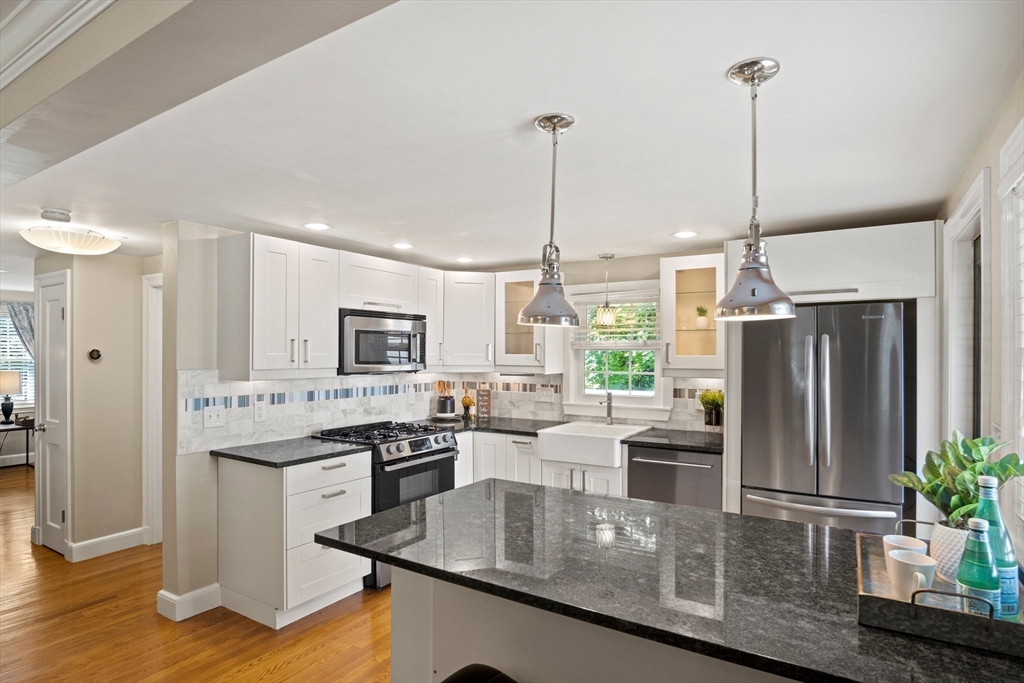12 Renwick Road Melrose, MA 02176 - Photo 7 of 40 a kitchen with stainless steel appliances granite countertop a refrigerator a sink dishwasher a stove and white cabinets with wooden floor