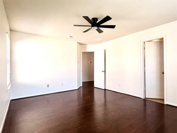 a view of a room with wooden floor and a ceiling fan