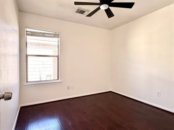 an empty room with wooden floor fan and windows