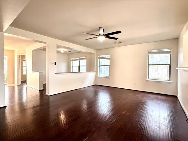 a view of an empty room with wooden floor and a window