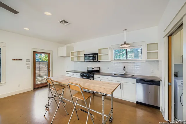 a kitchen with stainless steel appliances kitchen island a table and chairs in it