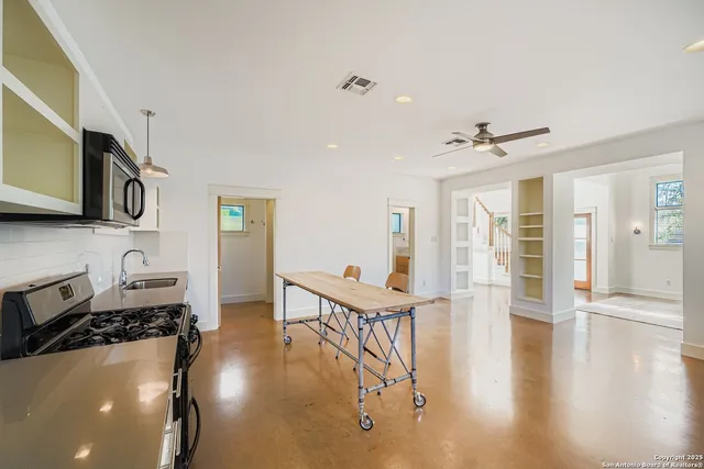 a view of a livingroom with furniture wooden floor kitchen view and a window
