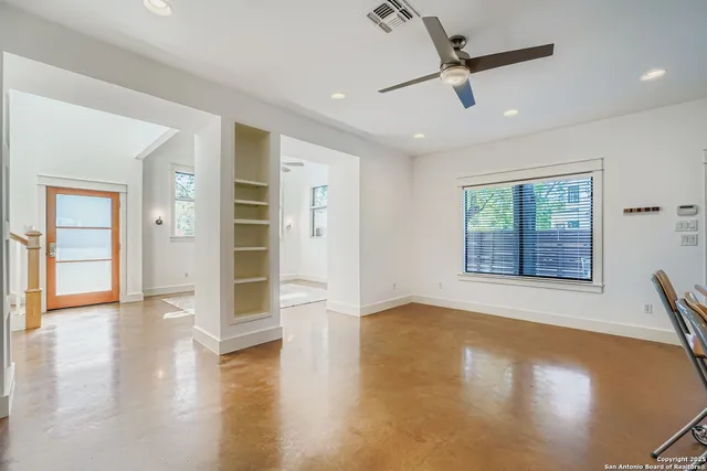 a view of an empty room with a window and wooden floor
