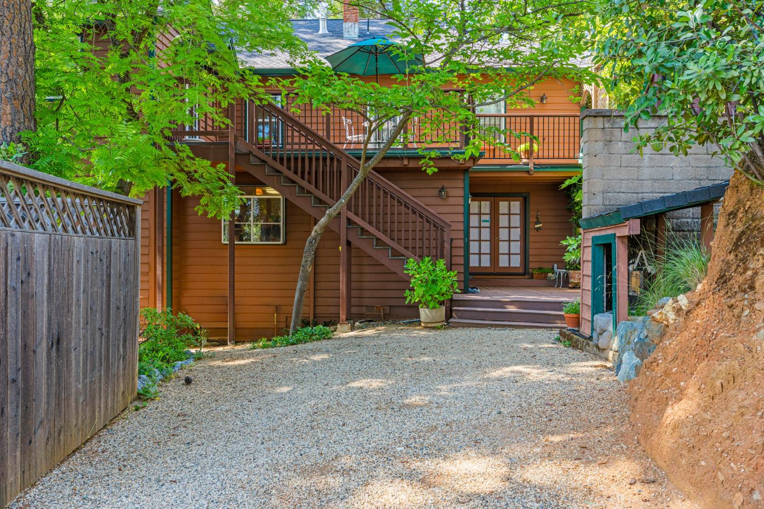5821 Spanish Flat Road Placerville, CA 95667 - Photo 57 of 97 a view of a wooden house with a small yard plants and large tree