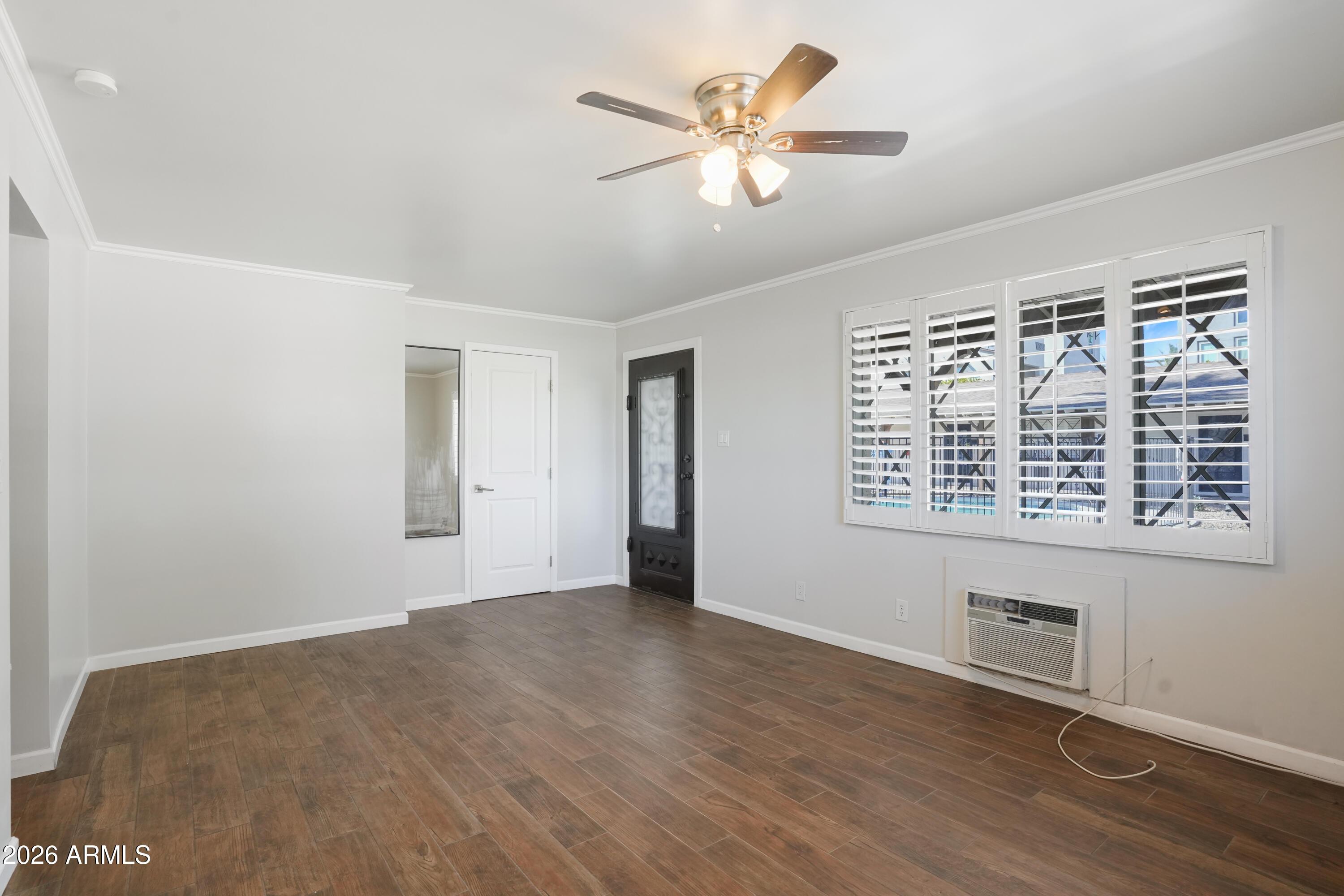 3426 North Miller Road, Unit 5 Scottsdale, AZ 85251 - Photo 10 of 11 an empty room with wooden floor chandelier fan and windows