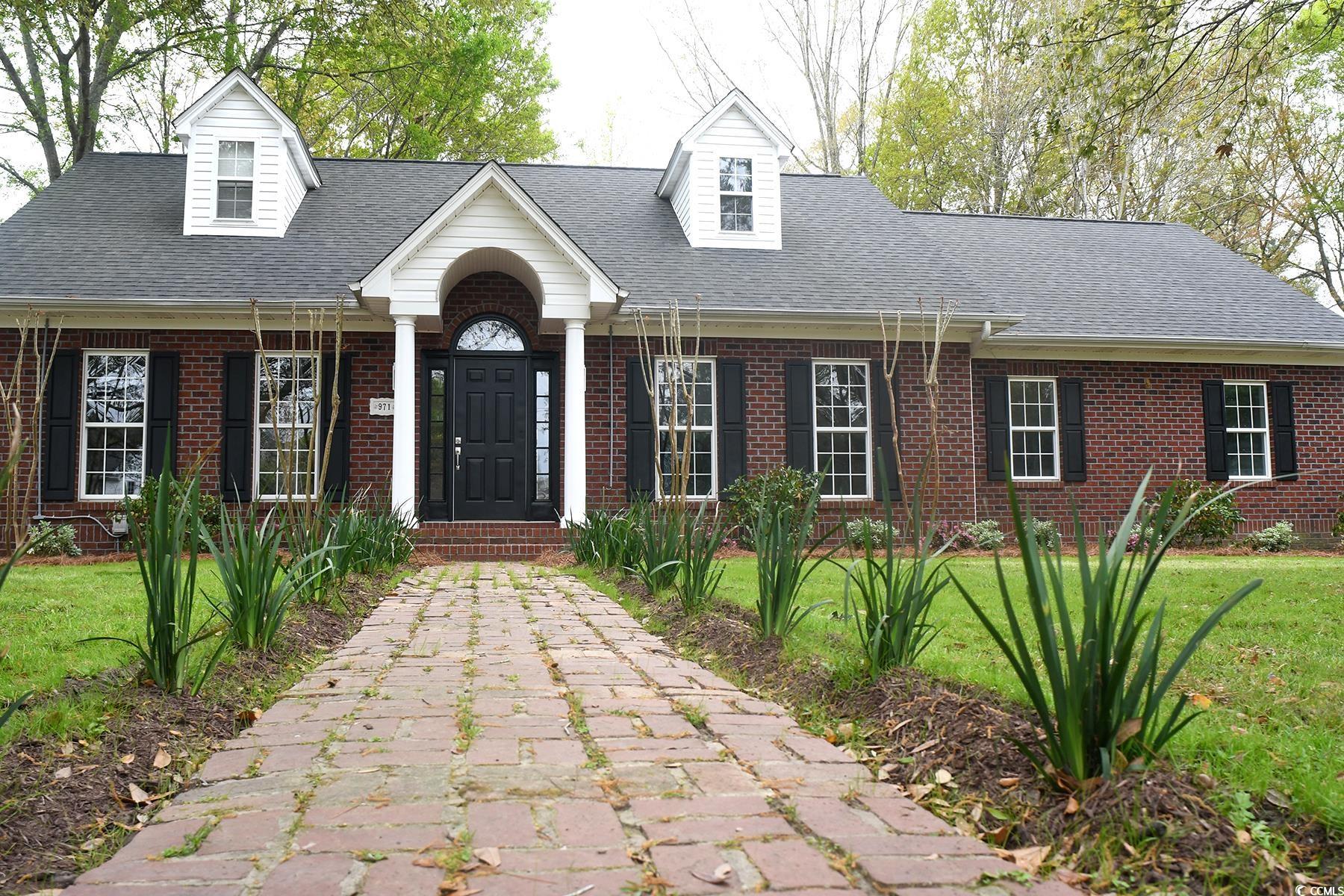 971 Folly Road Myrtle Beach, SC 29588 - Photo 1 of 25 Cape cod-style house featuring a shingled roof, a front lawn, and brick siding