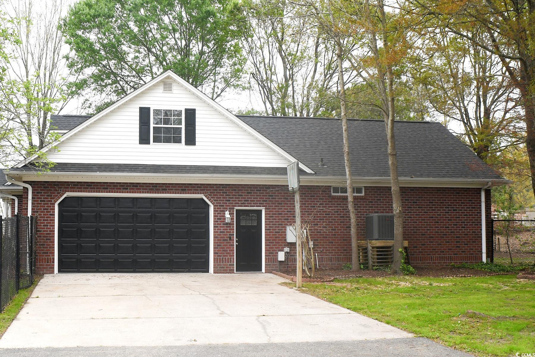 971 Folly Road Myrtle Beach, SC 29588 - Photo 25 of 25 Traditional-style home with roof with shingles, driveway, brick siding, a garage, and fence