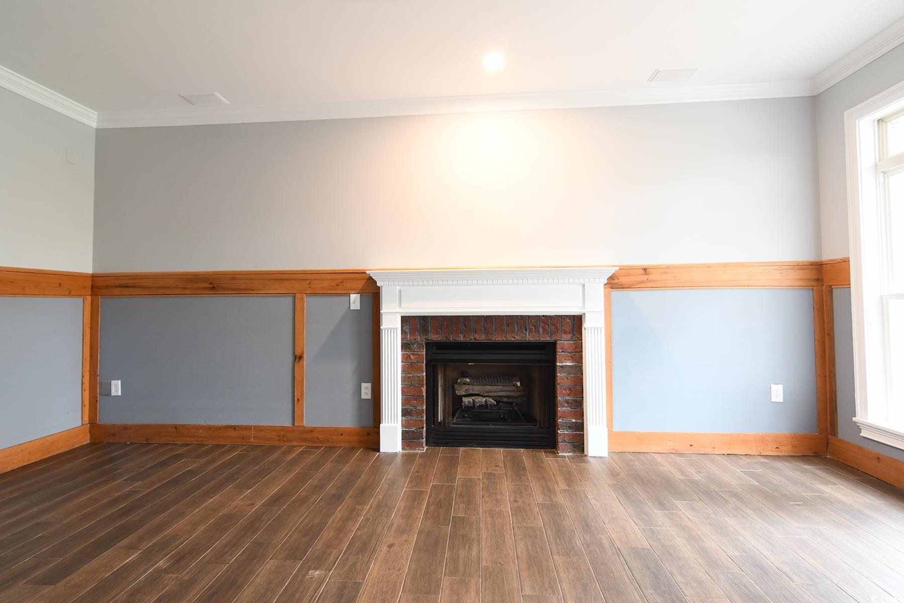 971 Folly Road Myrtle Beach, SC 29588 - Photo 4 of 25 Unfurnished living room with crown molding, wood finished floors, baseboards, and a brick fireplace