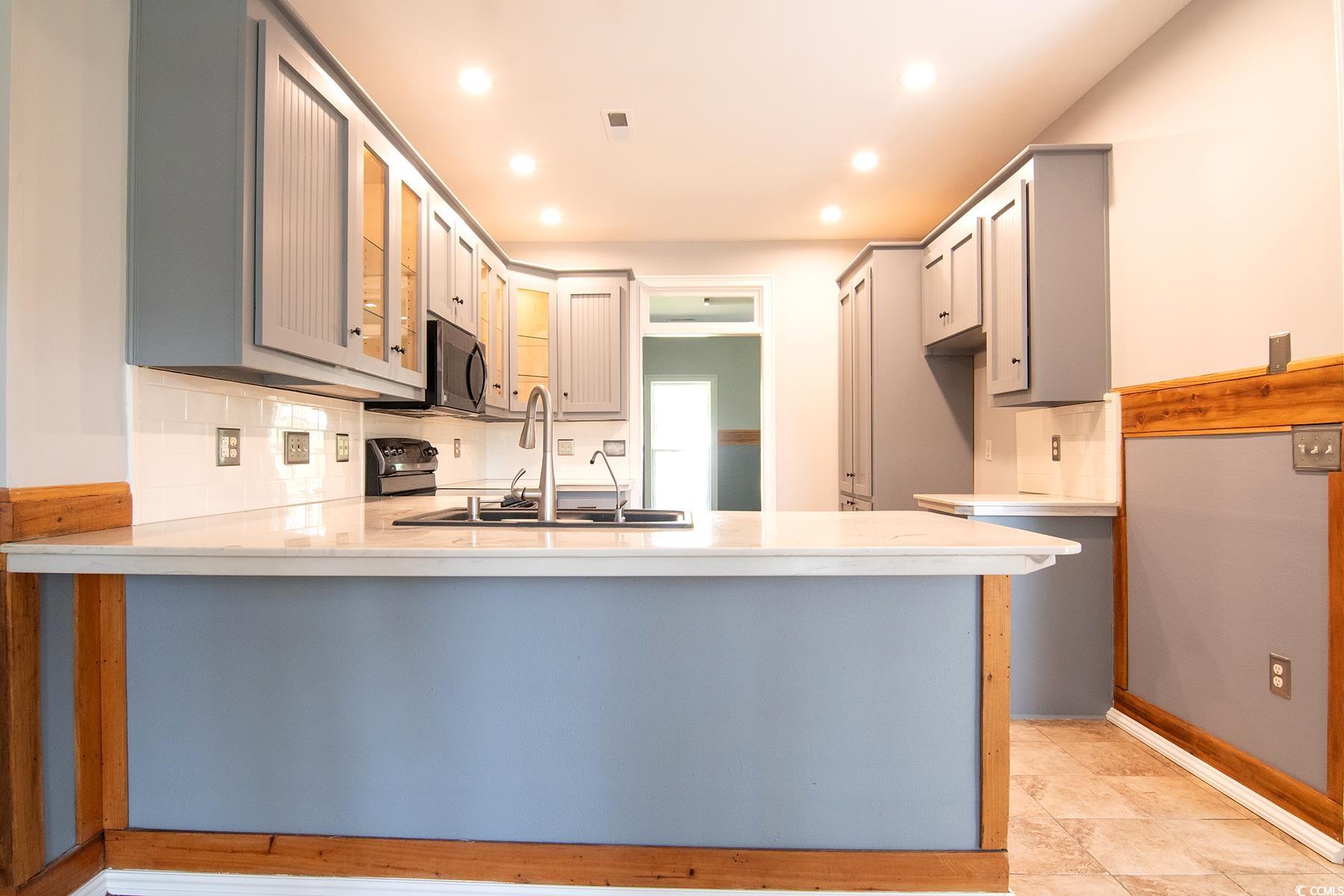 971 Folly Road Myrtle Beach, SC 29588 - Photo 10 of 25 Kitchen with gray cabinets, recessed lighting, a peninsula, glass insert cabinets, and light countertops
