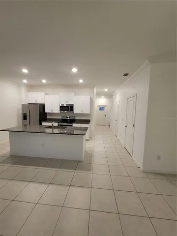 a large white kitchen with stainless steel appliances granite countertop a sink and a stove